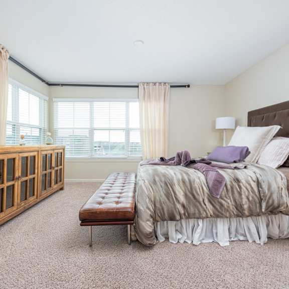 A bedroom with a large bed and a wooden cabinet.