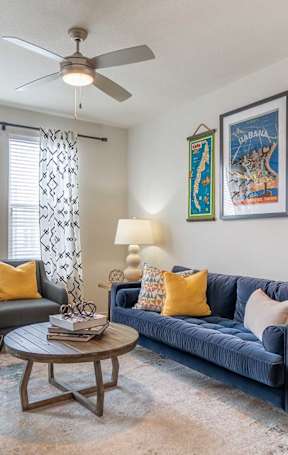 A living room with a blue couch, a coffee table, and a ceiling fan.