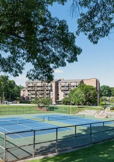 A tennis court surrounded by trees and buildings.