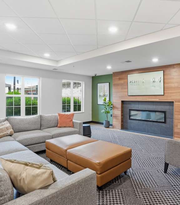 A living room with a grey couch, a brown ottoman, and a grey chair.