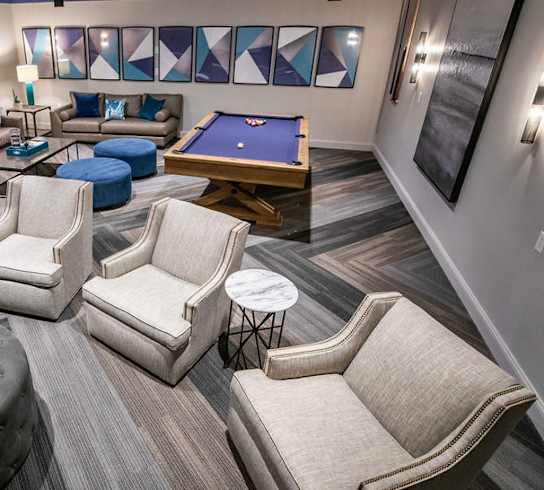 A room with a pool table and comfortable seating.