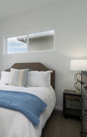 A bedroom with a large bed and a window overlooking a building.