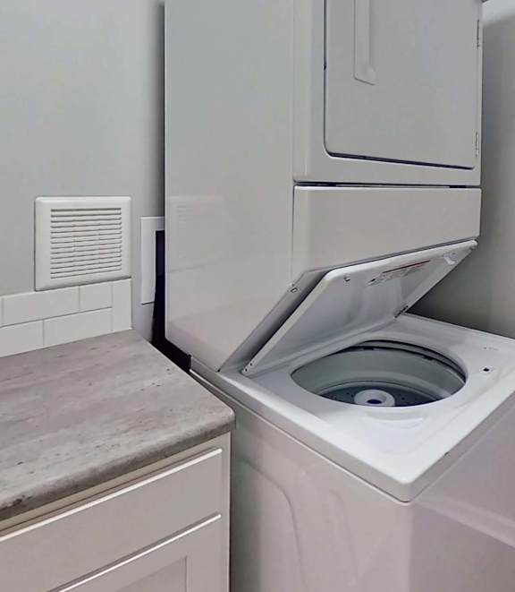 A white washing machine is installed in a bathroom.