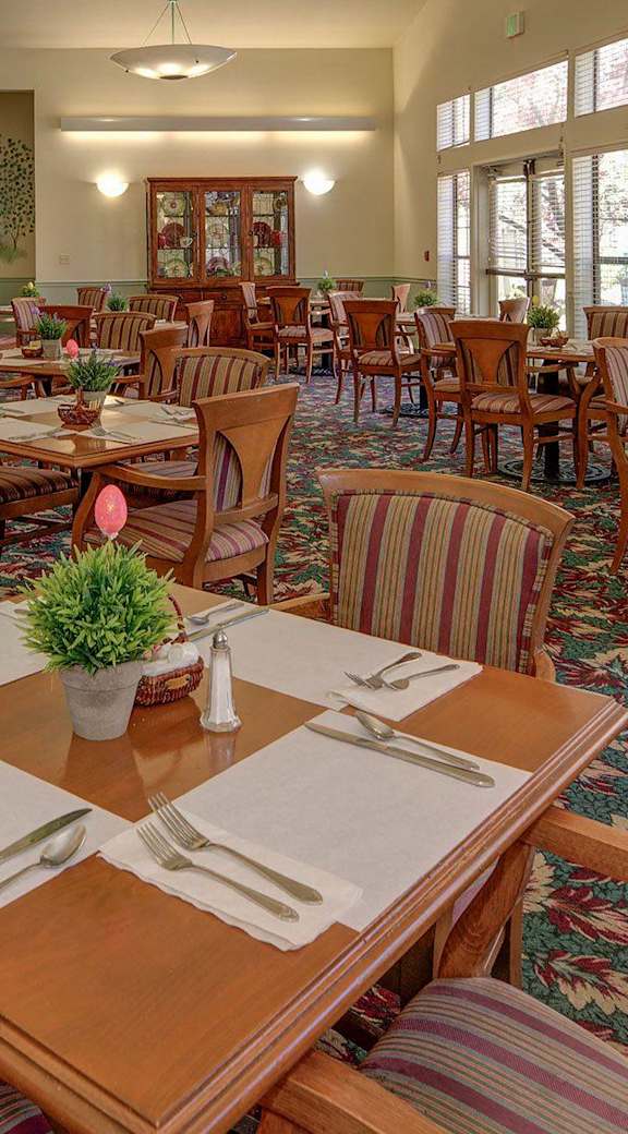 a large dining room with tables and chairs and windows  at Castle Vista Senior Duplex Community, Atwater, CA