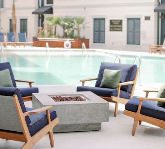 a swimming pool with chairs and a fire pit at The Merchant Apartments, South Carolina 29403