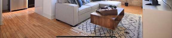 a living room with a couch and a table in front of a kitchen