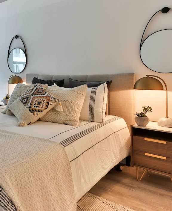 A bedroom with a large bed and a round mirror on the wall.