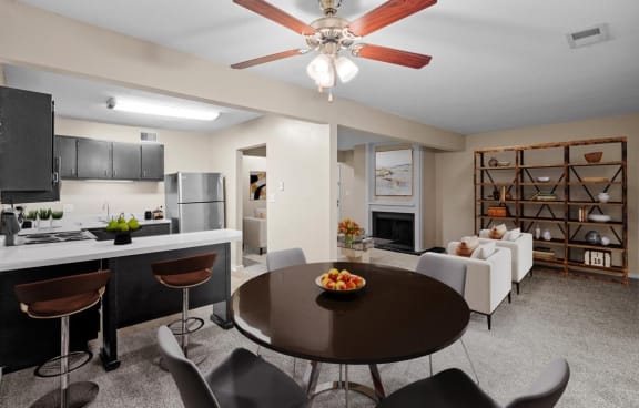 a living room and dining room with a kitchen and a ceiling fan