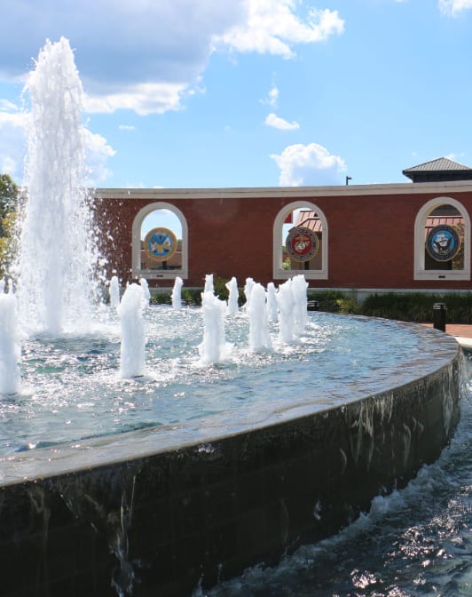 A fountain in front of a building with arched windows.