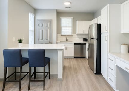 A kitchen with a white countertop and blue chairs.