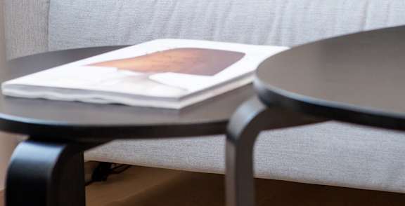 A chair with a teal cushion is in the center of a room with a table and a cactus.
