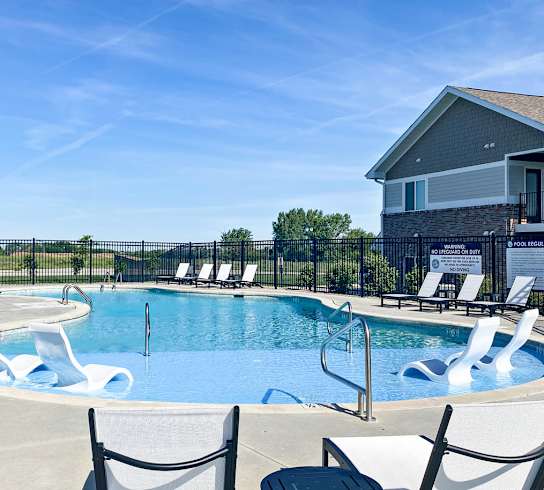 A pool with a slide and chairs around it.