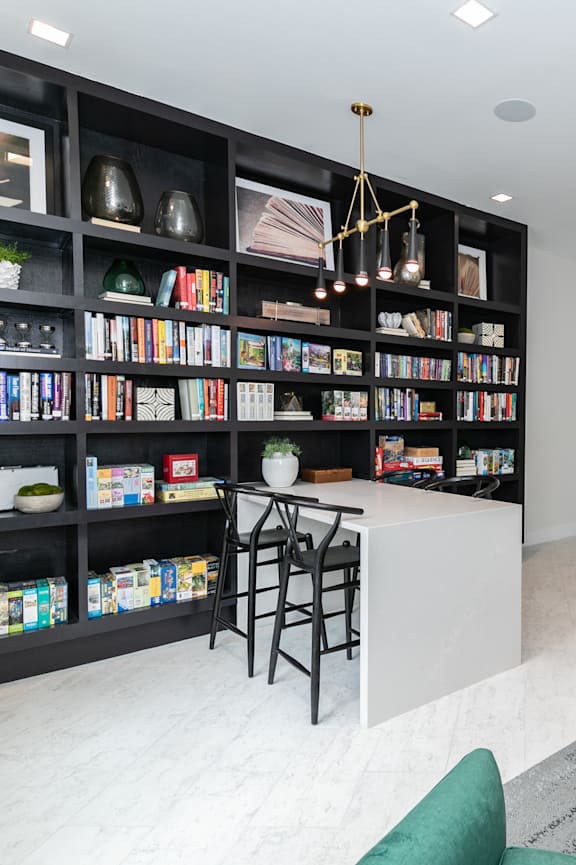A living room with a green couch, a coffee table, and a bookshelf filled with books.