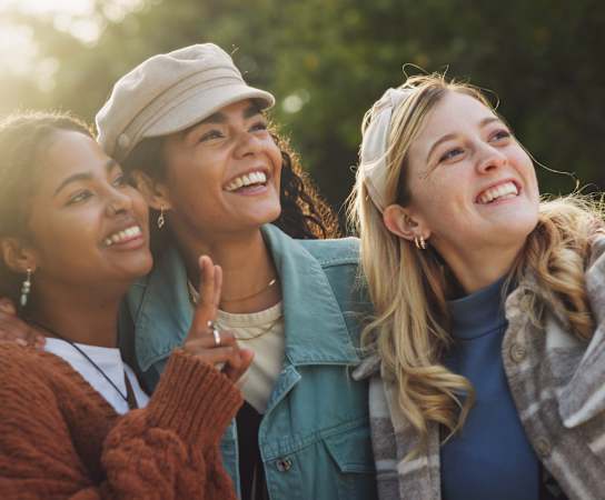 Three women are taking a selfie together outdoors.
