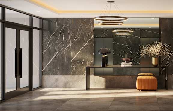 A modern office lobby with a marble wall and a circular light fixture.