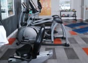 Thumbnail 15 of 23 - Fifteen 50 apartments near Las Vegas strip on site fitness center with modern orange and grey tile floor and exercise equipment facing wall TVs.