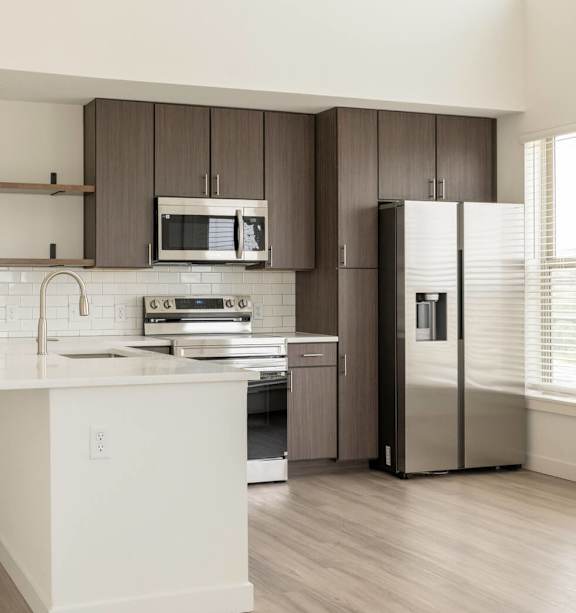 A modern kitchen with white countertops and stainless steel appliances.
