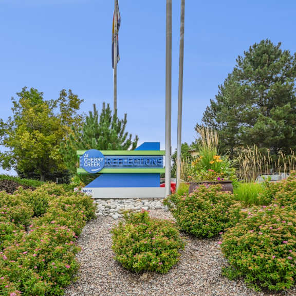 A garden with a sign that says "Buffalo Creek School" in front of a flag pole.