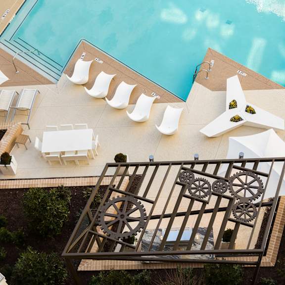 arial view of a swimming pool with white lounge chairs and umbrellas