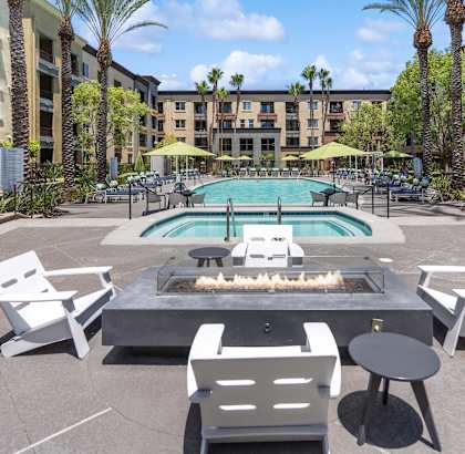 A pool area with a fire pit and chairs. at The Kitt at Warner Center Apartments, Woodland Hills, CA