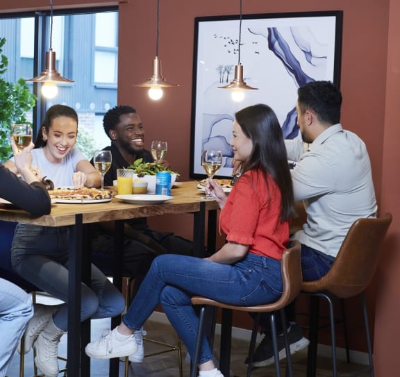 a group of people sitting around a table eating food and drinking wine