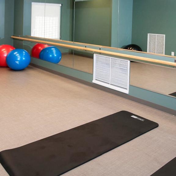 A yoga studio with a mirror, exercise balls, and yoga mats.
