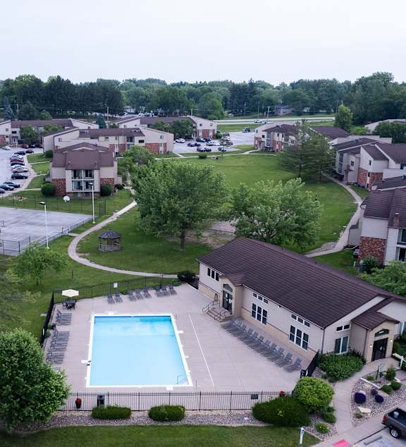 A large swimming pool is surrounded by a small building and a parking lot. at Indian Ridge Apartments, Iowa, 52807