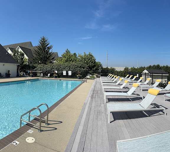 A large swimming pool with lounge chairs and a building in the background.