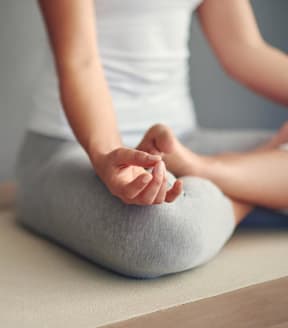 a woman sitting on a yoga mat with her hands on her lap