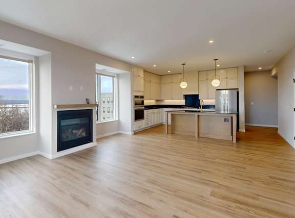 A spacious living room with a fireplace and a dining area at Ardor on the Bluffs South Loop Residences Apartments, Bloomington, Minnesota