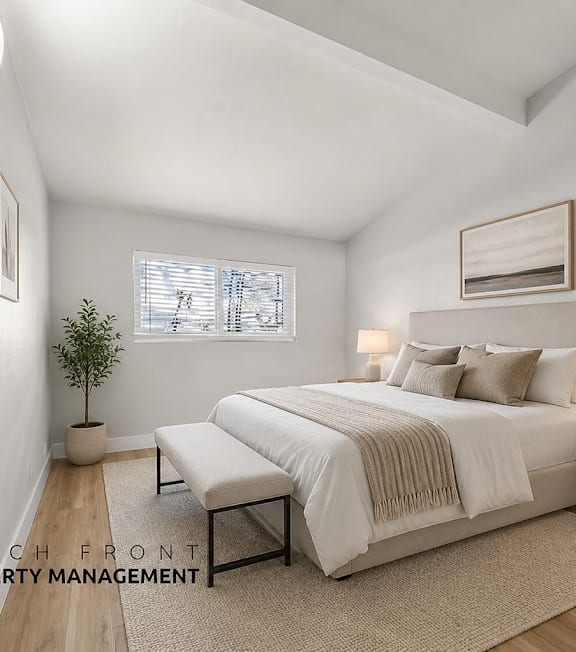 A well-lit bedroom with a large bed and a small plant on the side table.