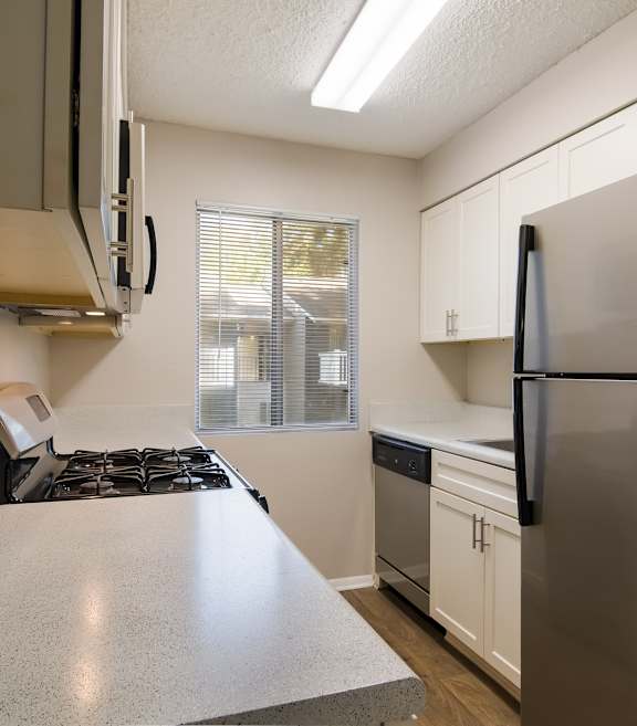 Kitchen with gas stove, fridge, and white cabinets at Dunwoody Pointe