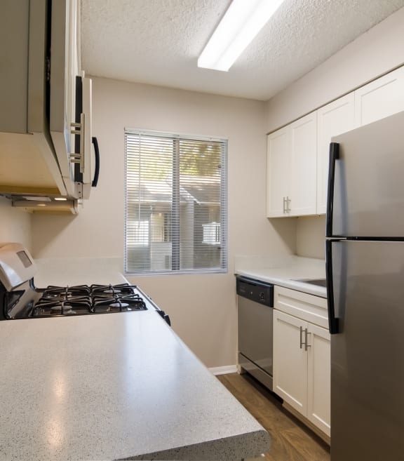 Kitchen with gas stove, fridge, and white cabinets at Dunwoody Pointe