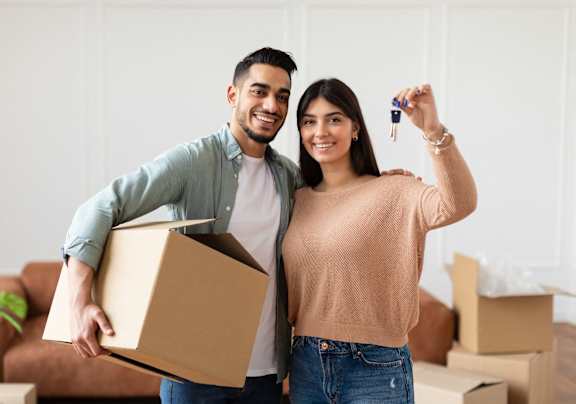 A man and woman are standing in a room with boxes, holding a key and a box at Promontory, Tucson, 85704