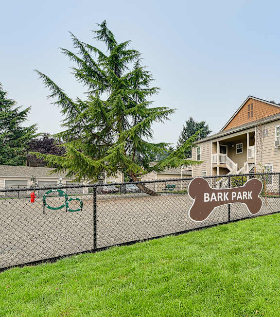 A sign that says Bark Park is in front of a fence.