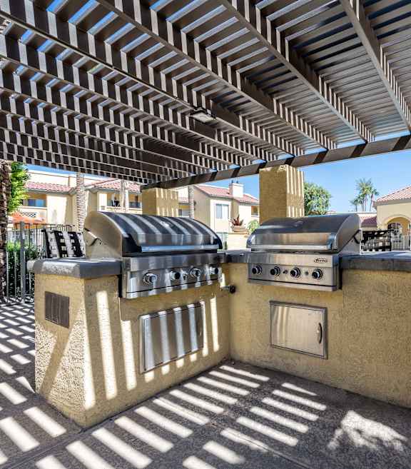 A patio with a grill and a pergola.
