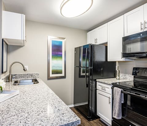 The Oaks Apartments -Kitchen with White Cabinets, Wood Style Flooring and Black Appliances