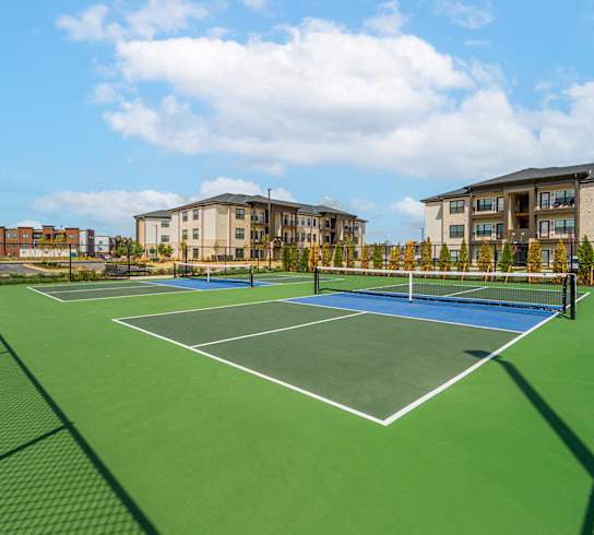 a tennis court with apartments in the background