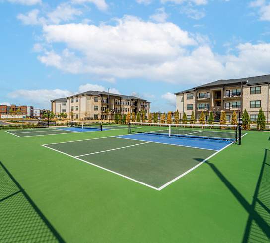 a tennis court with apartments in the background