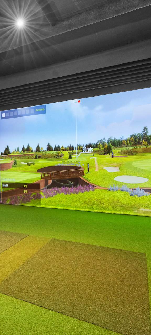A room with a golf simulator and two chairs.