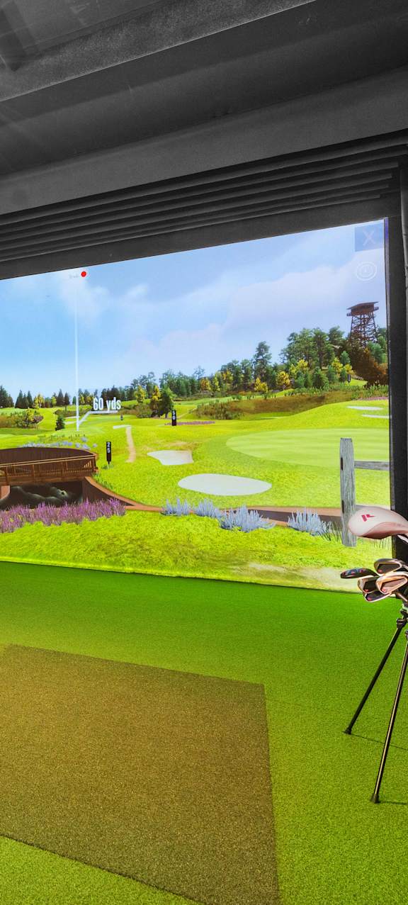A room with a golf simulator and two chairs.