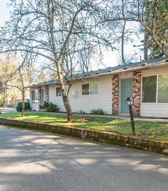 A residential house with a driveway and trees.