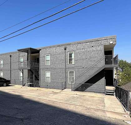 a grey apartment building with stairs and a parking lot