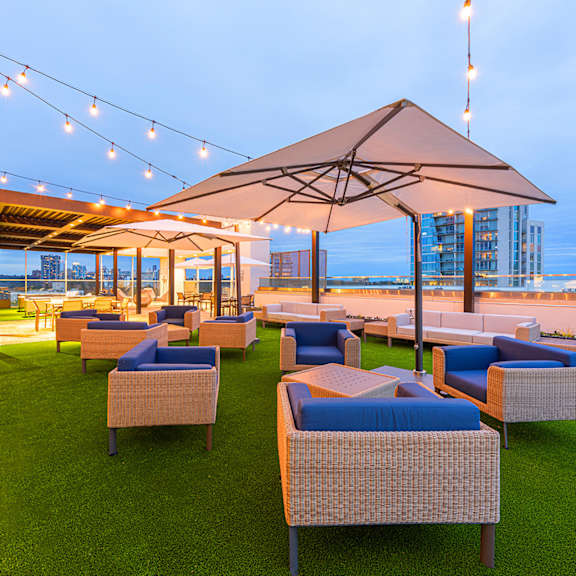 A patio with a lawn and chairs under umbrellas.
