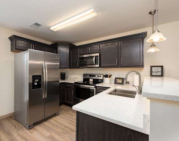 A kitchen with a stainless steel refrigerator and black cabinets.
