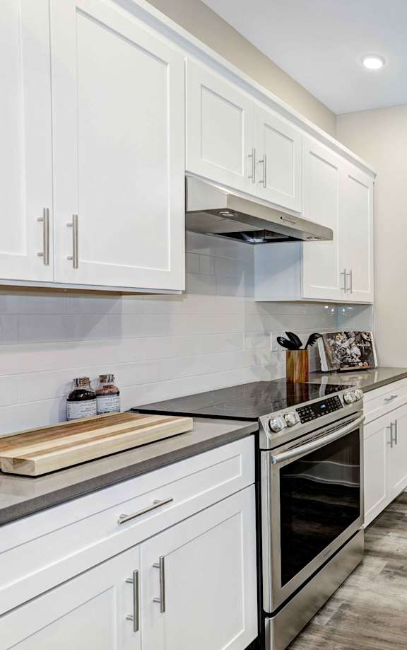 A modern kitchen with white cabinets and a stainless steel oven.