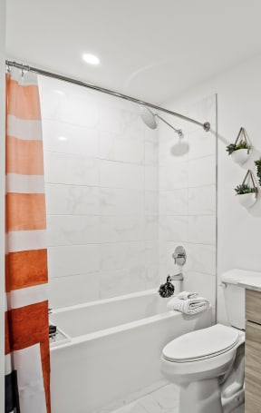 a bathroom with white walls and a white toilet next to a bathtub with a shower curtain at Altis Grand Lake Willis, Florida