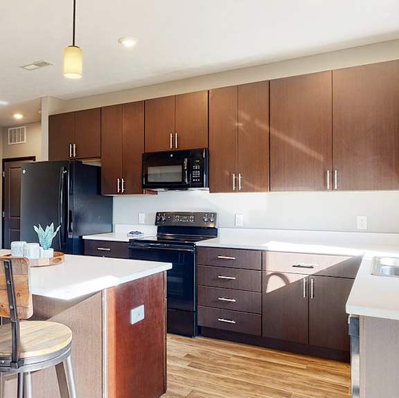 a kitchen with dark brown wooden cabinets and a bar with two chairs