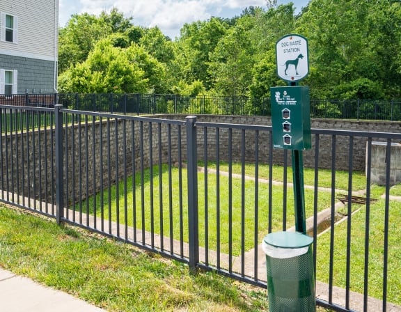 a black wrought iron fence with a green sign on it and a yard behind it