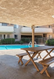 a pool with a picnic table in front of an apartment building our apartments have a swimming pool and picnic table